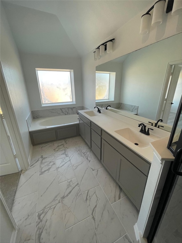 bathroom featuring vanity, lofted ceiling, and a bathing tub