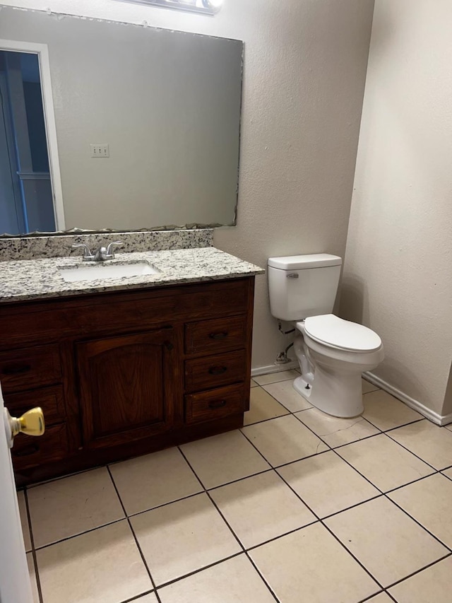 bathroom with toilet, vanity, and tile patterned flooring