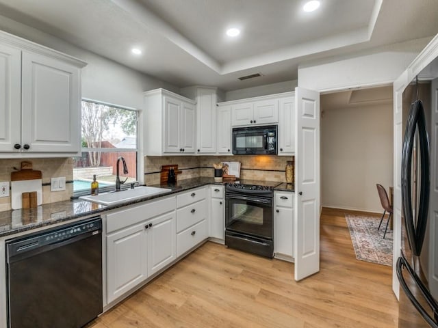 kitchen featuring black appliances, white cabinets, sink, and a tray ceiling