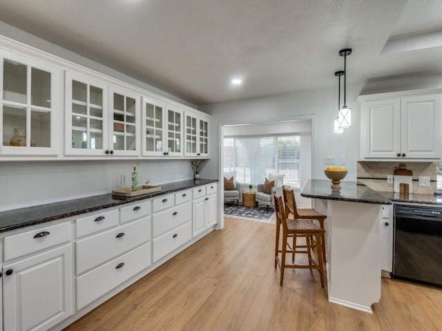 kitchen featuring pendant lighting, a kitchen bar, white cabinetry, black dishwasher, and light wood-type flooring