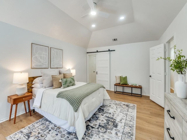 bedroom with ceiling fan, light hardwood / wood-style flooring, lofted ceiling, and a barn door