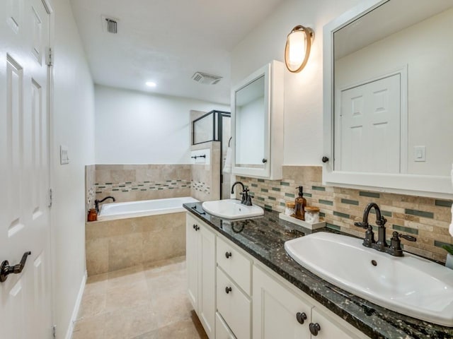 bathroom with tiled bath, tile patterned flooring, and vanity