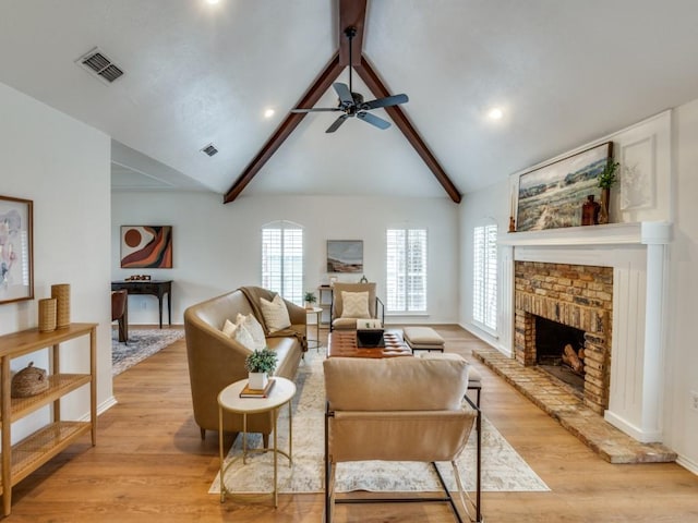 living room with ceiling fan, lofted ceiling with beams, a fireplace, and light hardwood / wood-style floors