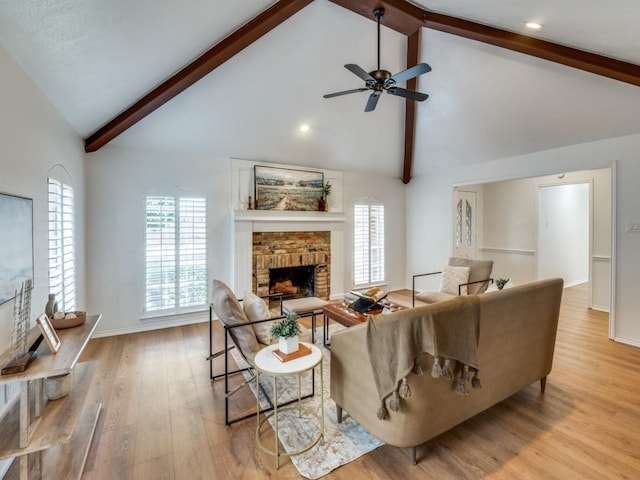 living room with ceiling fan, a fireplace, light hardwood / wood-style floors, beamed ceiling, and high vaulted ceiling