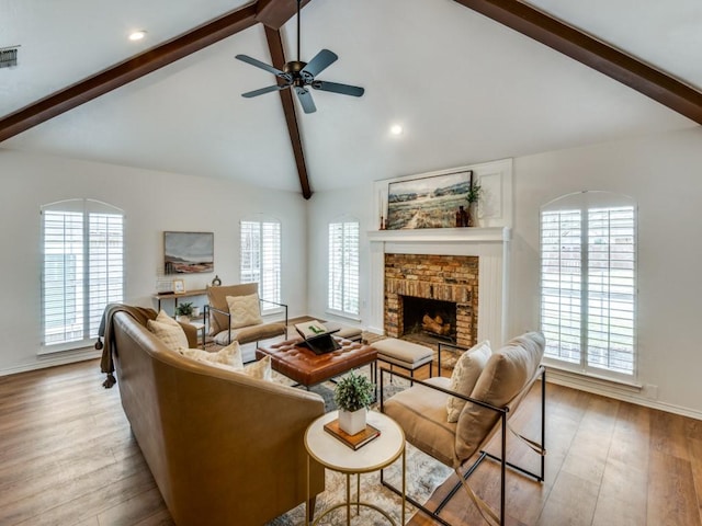 living room with a brick fireplace, lofted ceiling with beams, ceiling fan, and light wood-type flooring