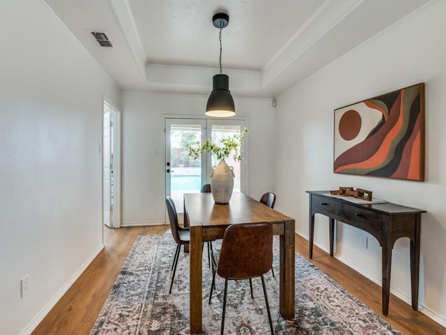 dining room with hardwood / wood-style floors and a raised ceiling