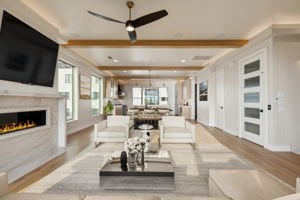 living room featuring ceiling fan, crown molding, beamed ceiling, and light wood-type flooring