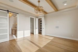 unfurnished room with a chandelier, beam ceiling, a barn door, and hardwood / wood-style floors