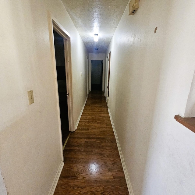 hallway with a textured ceiling and dark hardwood / wood-style flooring