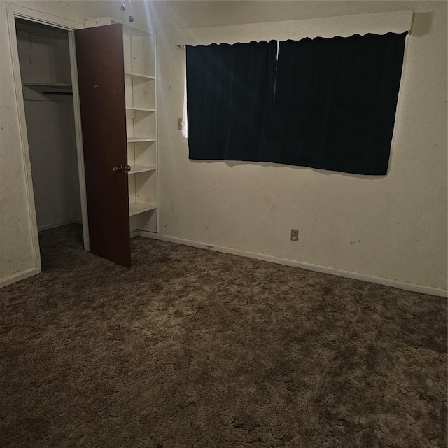 unfurnished bedroom featuring a closet and dark carpet