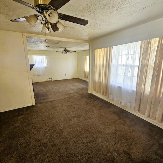 unfurnished room with ceiling fan, dark carpet, and a textured ceiling