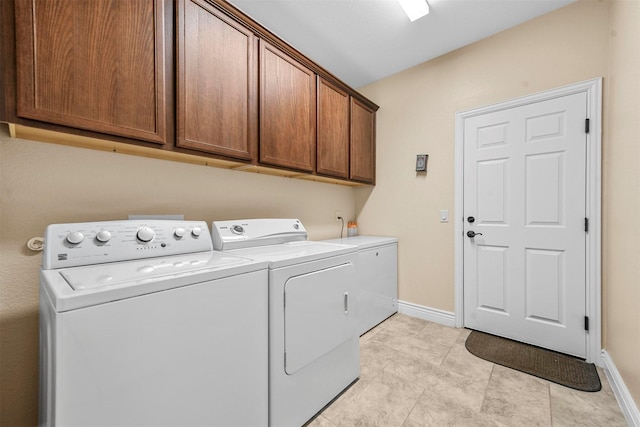 clothes washing area with cabinets, light tile patterned floors, and washing machine and clothes dryer