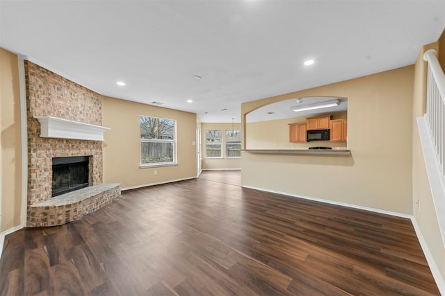 unfurnished living room featuring a brick fireplace and dark hardwood / wood-style flooring