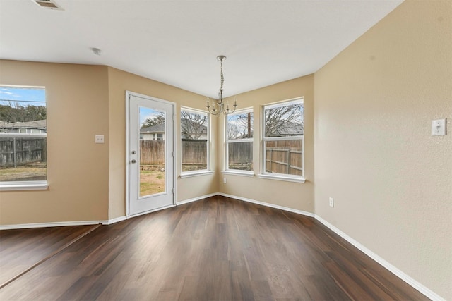 unfurnished dining area with dark wood-type flooring and a notable chandelier