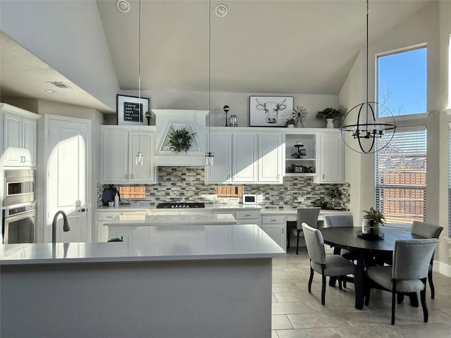 kitchen with decorative light fixtures, a notable chandelier, oven, vaulted ceiling, and white cabinets