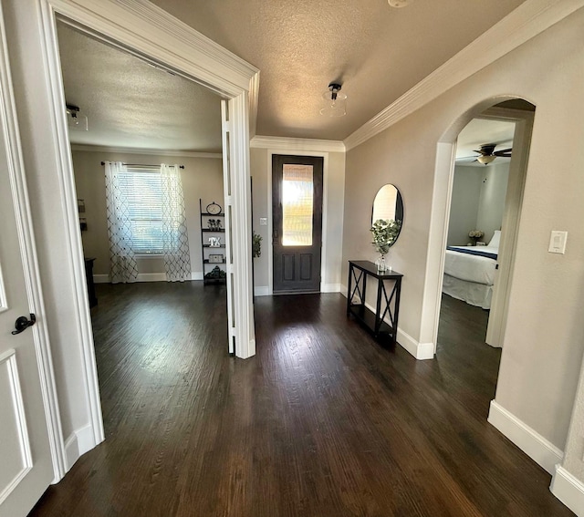 entryway featuring a textured ceiling, dark wood-type flooring, crown molding, and ceiling fan