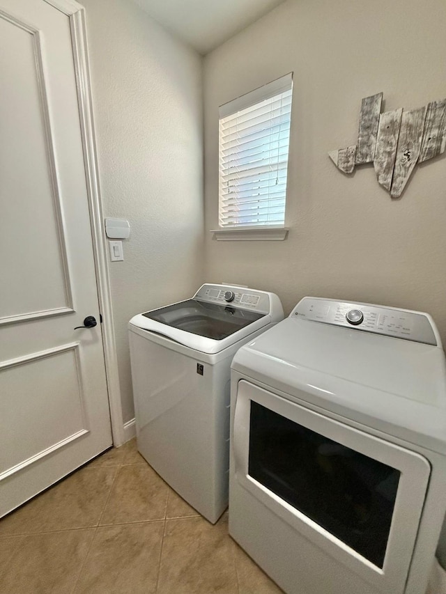 clothes washing area with light tile patterned floors and independent washer and dryer