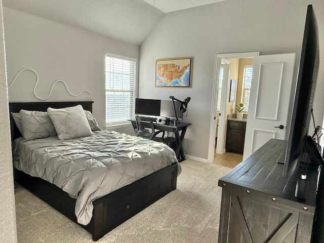 bedroom with connected bathroom, light carpet, and vaulted ceiling