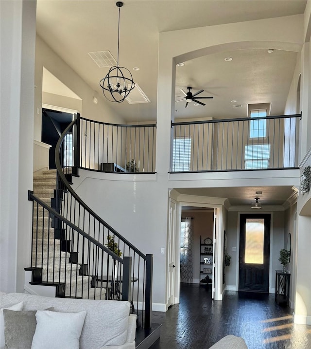 foyer with dark wood-type flooring and ceiling fan with notable chandelier