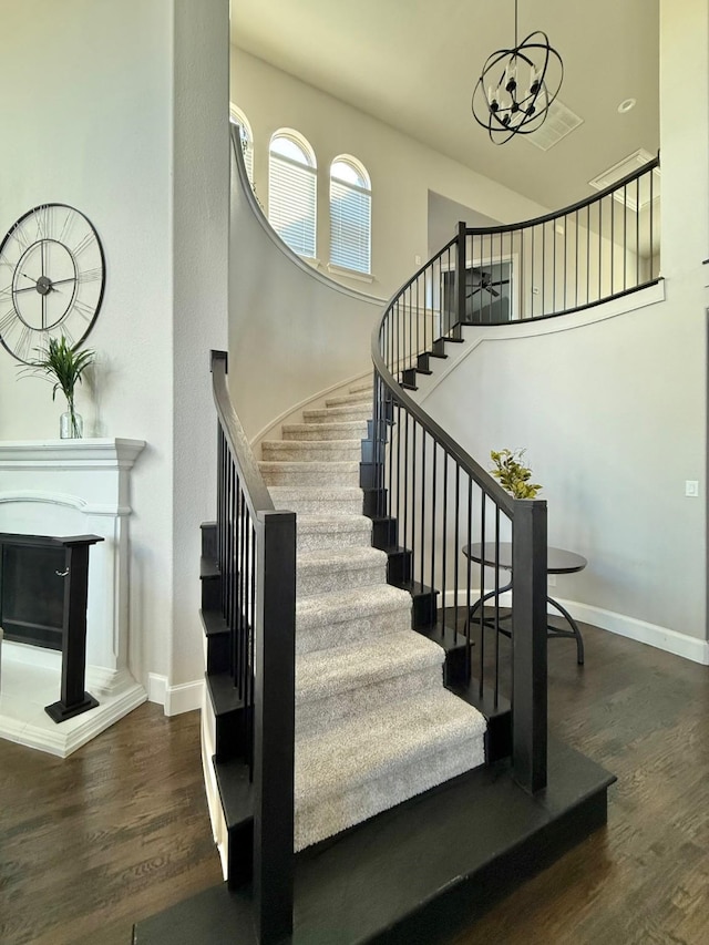 staircase with wood-type flooring and an inviting chandelier