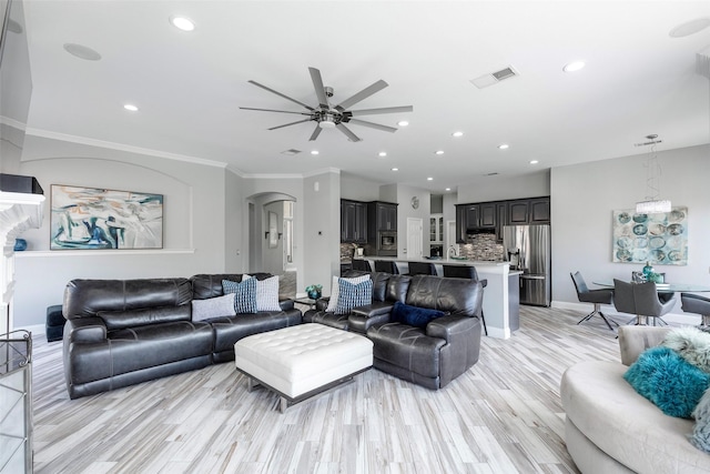 living room featuring visible vents, recessed lighting, arched walkways, light wood-style floors, and crown molding