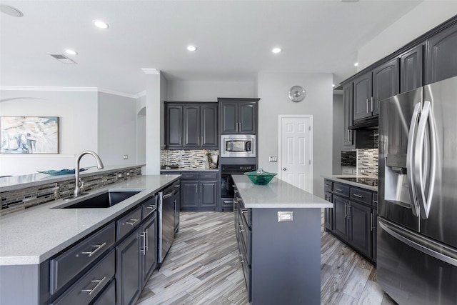 kitchen featuring visible vents, an island with sink, a sink, black appliances, and backsplash