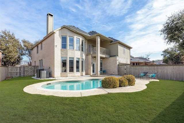 back of property with a lawn, a chimney, a fenced backyard, and a balcony