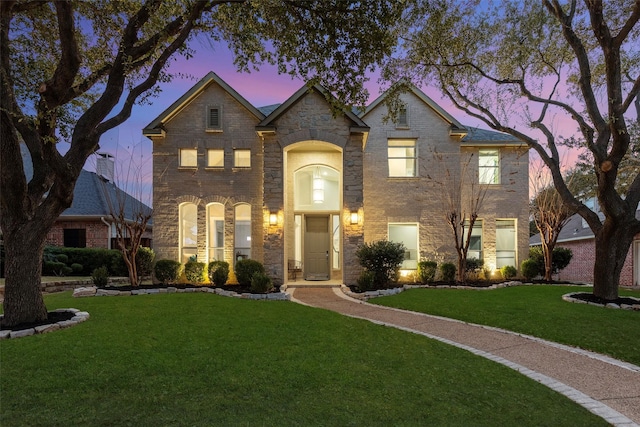 view of front of home featuring brick siding and a yard