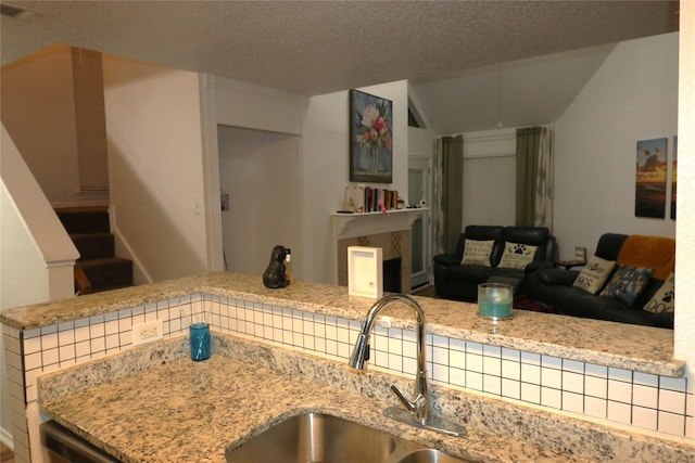 kitchen featuring light stone countertops, sink, and a textured ceiling