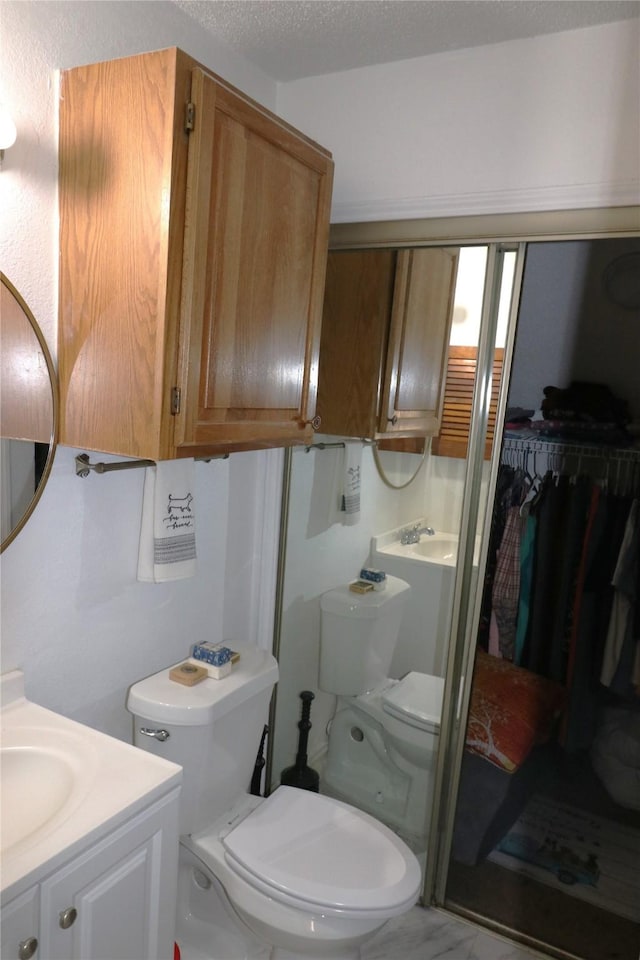 bathroom with a textured ceiling, toilet, and vanity