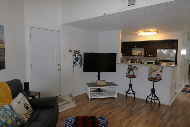 living room with a textured ceiling and dark hardwood / wood-style flooring