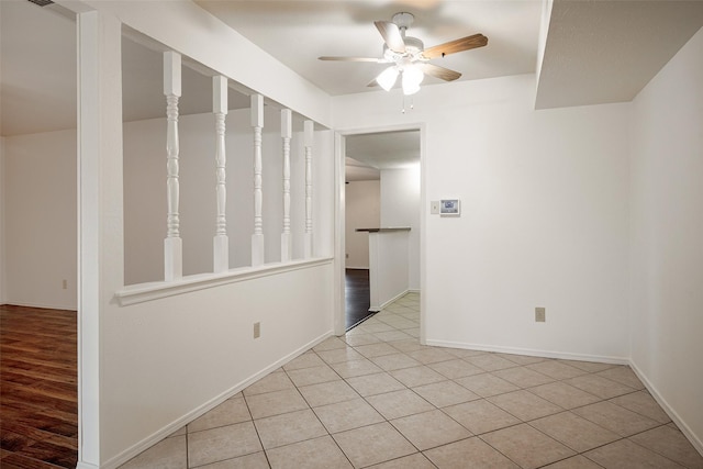 spare room with a ceiling fan, light tile patterned flooring, and baseboards