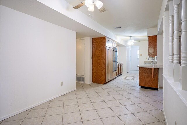 kitchen featuring light tile patterned floors, kitchen peninsula, ceiling fan, stainless steel appliances, and sink