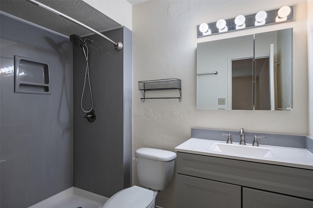 bathroom with a stall shower, a textured wall, vanity, and toilet