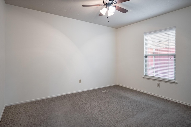 empty room featuring dark carpet, a ceiling fan, and baseboards