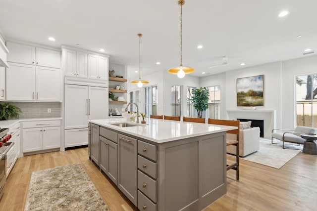 kitchen featuring white cabinetry, sink, paneled fridge, gray cabinets, and a kitchen island with sink