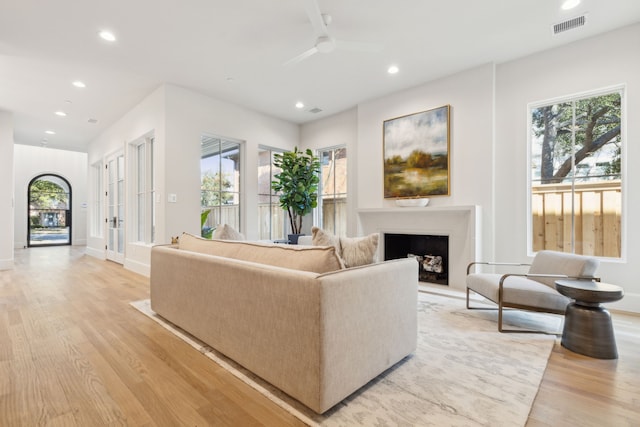 living room featuring light wood-type flooring, ceiling fan, and french doors