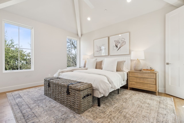 bedroom featuring hardwood / wood-style flooring, multiple windows, and lofted ceiling with beams