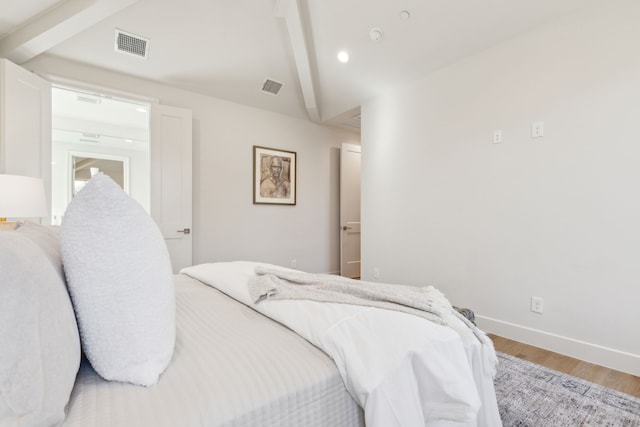 bedroom with light hardwood / wood-style flooring and vaulted ceiling with beams