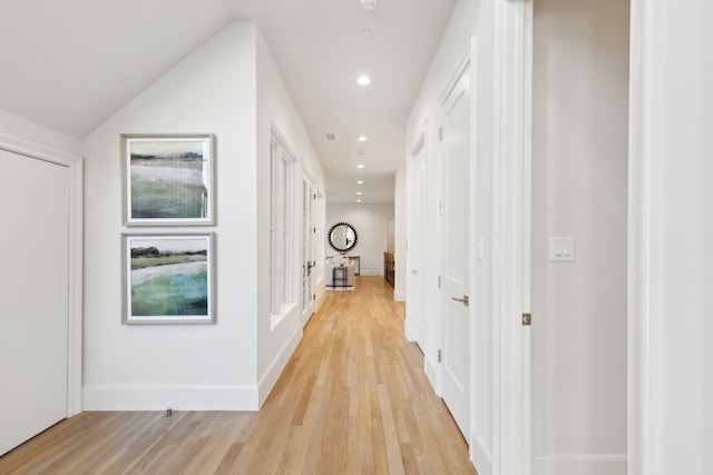 hallway featuring vaulted ceiling and light hardwood / wood-style flooring