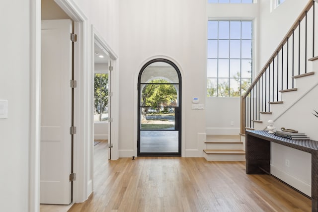 entryway with light hardwood / wood-style floors and a towering ceiling