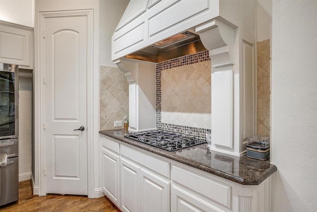 kitchen featuring white cabinets, black gas cooktop, dark stone counters, and light wood-type flooring