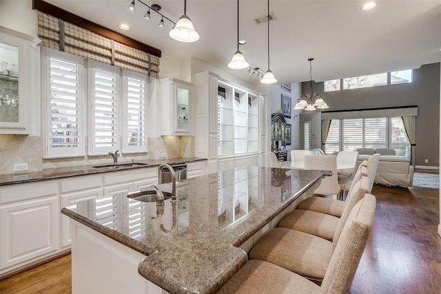 kitchen featuring a notable chandelier, an island with sink, white cabinets, and sink