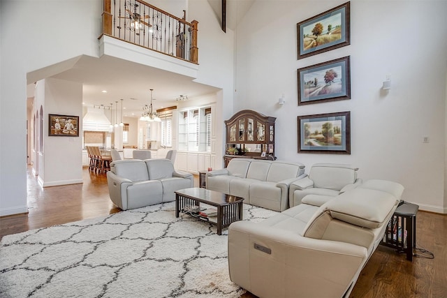 living room featuring dark hardwood / wood-style flooring, a towering ceiling, and a notable chandelier