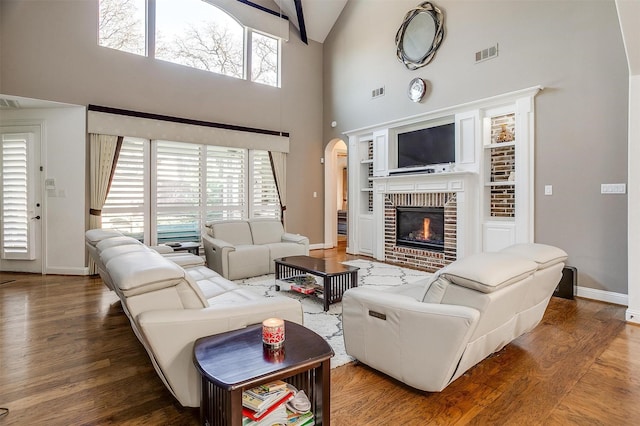 living room with plenty of natural light, hardwood / wood-style floors, a towering ceiling, and a fireplace