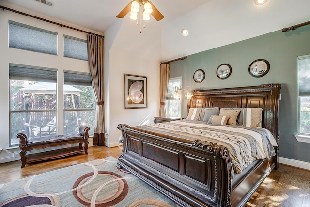 bedroom featuring ceiling fan, hardwood / wood-style floors, and high vaulted ceiling