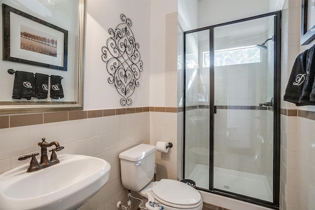 bathroom featuring sink, walk in shower, tile walls, and toilet