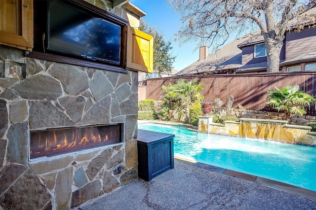 view of pool featuring pool water feature and an outdoor stone fireplace