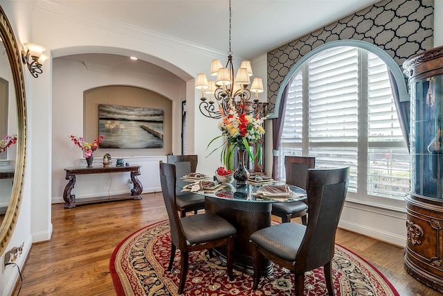 dining room with ornamental molding, a healthy amount of sunlight, an inviting chandelier, and wood-type flooring