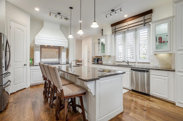 kitchen with light wood-type flooring, white cabinetry, a center island with sink, and appliances with stainless steel finishes